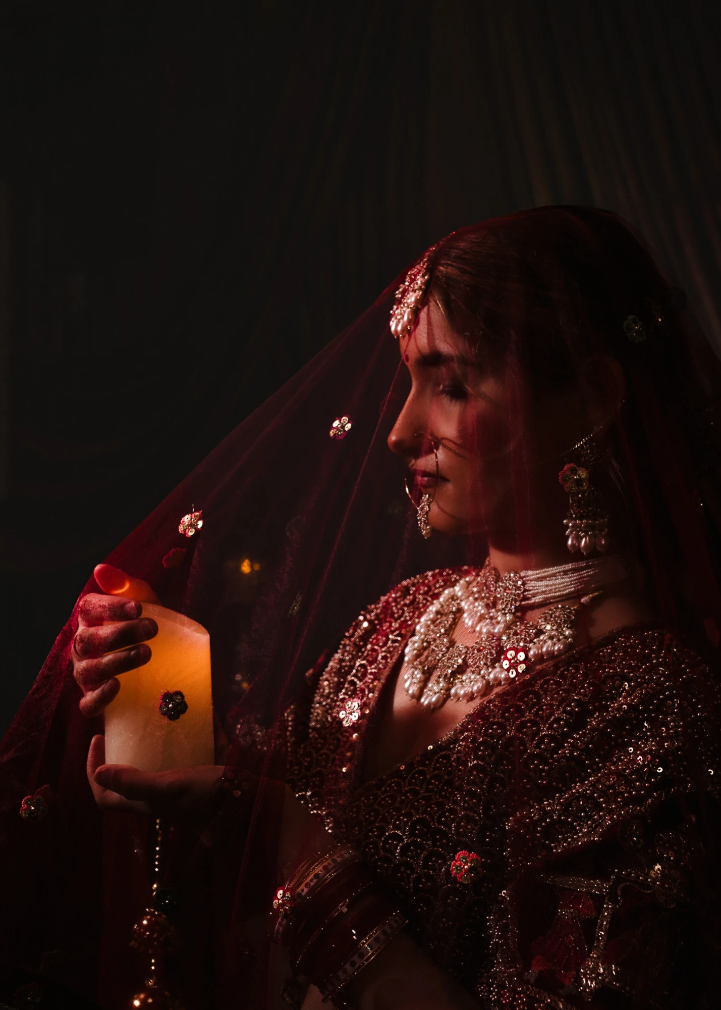 Traditional Riwaaz bride with candlelight, heritage jewelry and red lehenga